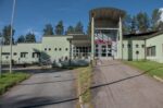 Hotellirakennuksen julkisivu. Keskellä katettu sisäänkäynti ja oven päällä nimi Tulikettu. Siitä vasemmalle laskeutuu portaikko ja yksikerroksinen rakennus laskeutuu kolmessa osassa kohti kuvan vasenta reunaa. Oikealla sisäänkäynnille johtava asfalttiluiska ja kuvaajaa kohti oikeassa reunassa suorakulmaisesti tuleva yksikerroksinen siipi. Rakennuksen takana on mäntyjä, etualalla asfalttipiha.